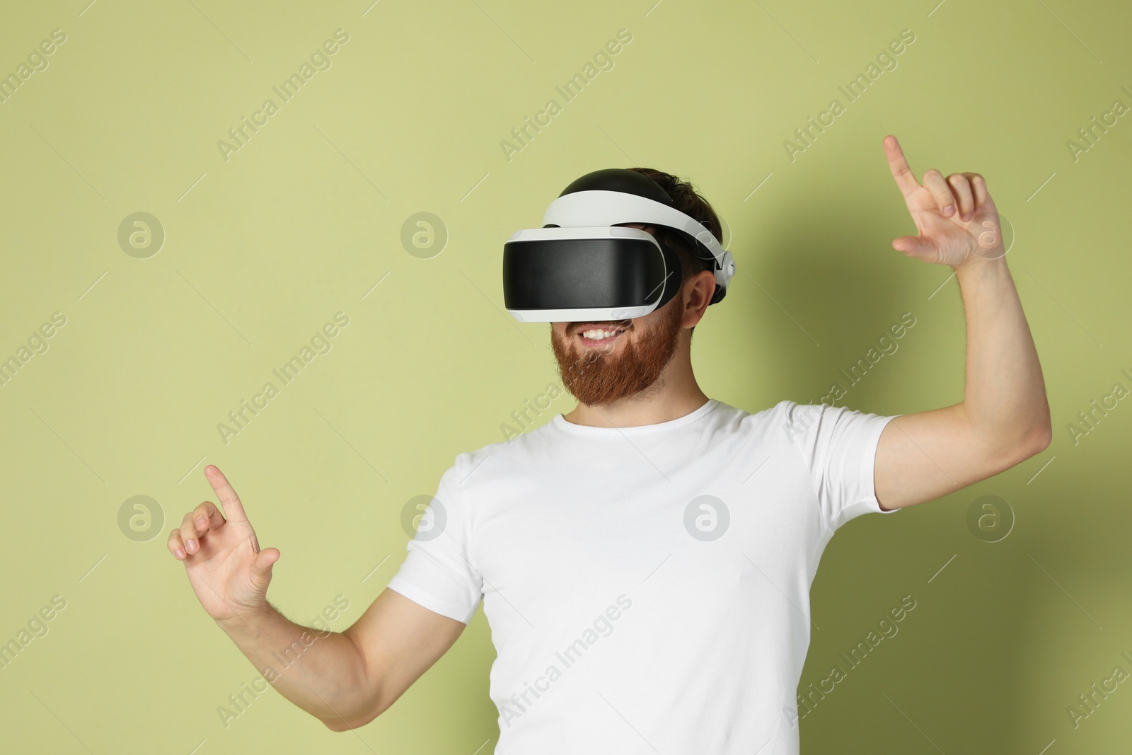 Photo of Smiling man using virtual reality headset on pale green background