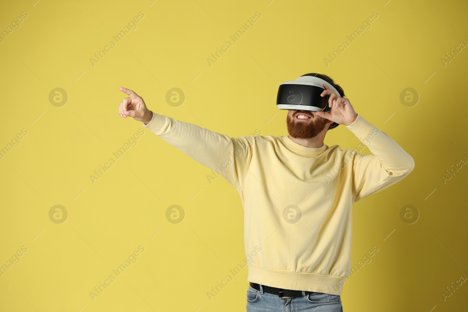 Photo of Man using virtual reality headset on pale yellow background