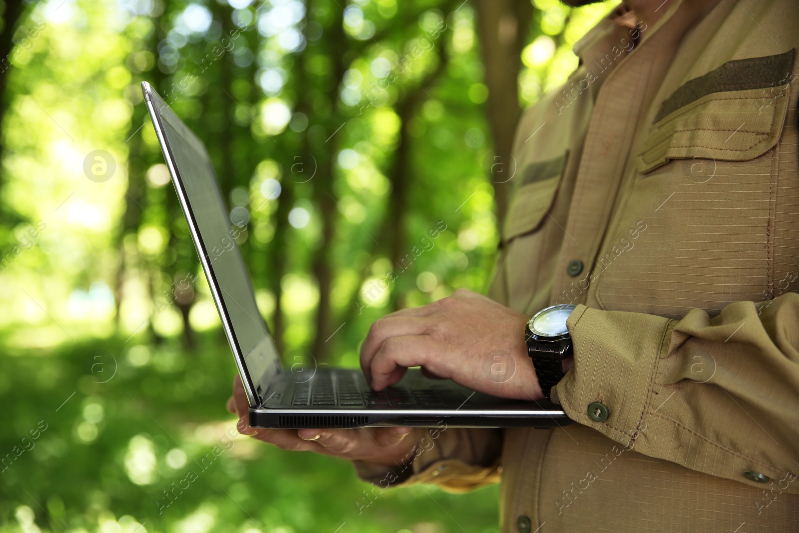 Photo of Forester with laptop examining plants in forest, closeup