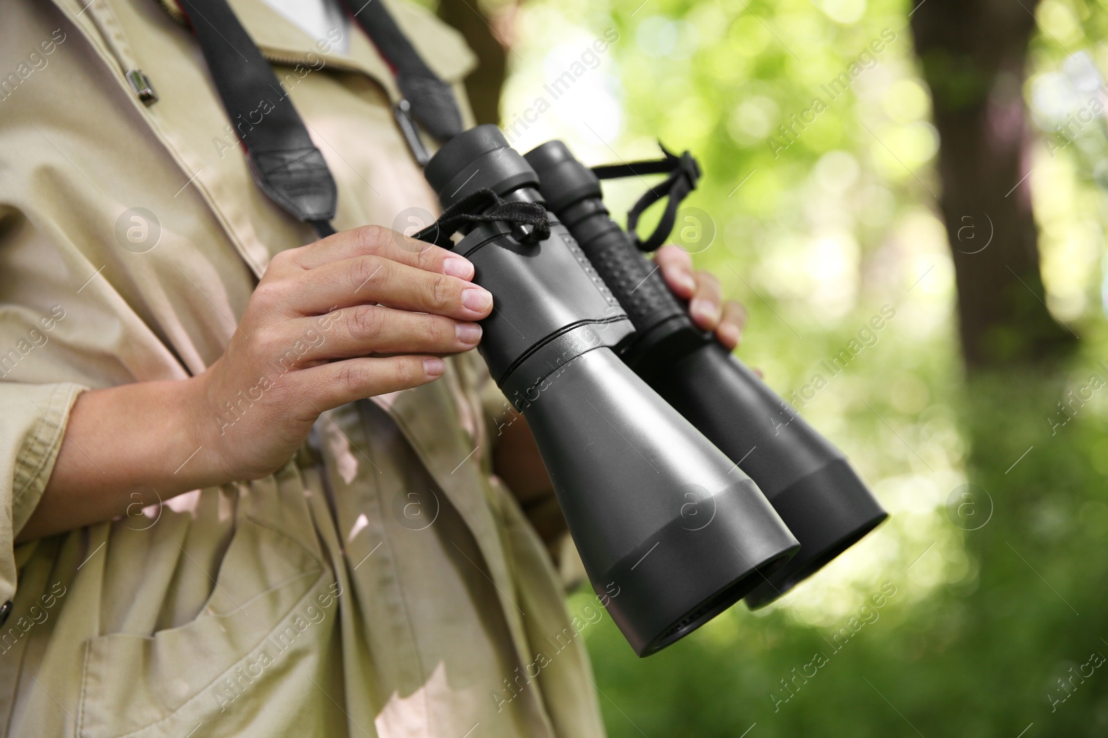 Photo of Forester with binoculars examining plants in forest, closeup