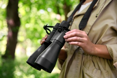 Photo of Forester with binoculars examining plants in forest, closeup