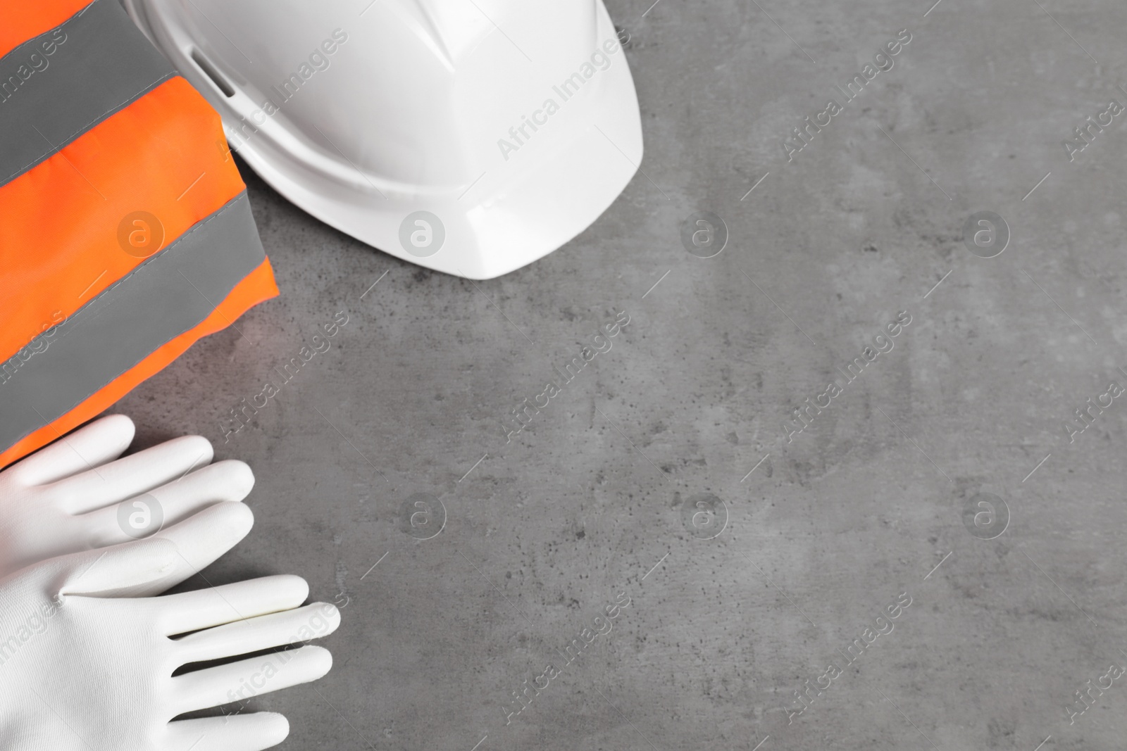 Photo of Reflective vest, hard hat and protective gloves on gray background, flat lay. Space for text