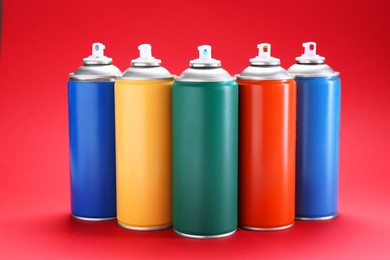 Photo of Many spray paint cans on red background