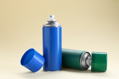Photo of Two spray paint cans on beige background
