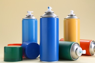 Photo of Many spray paint cans on beige background