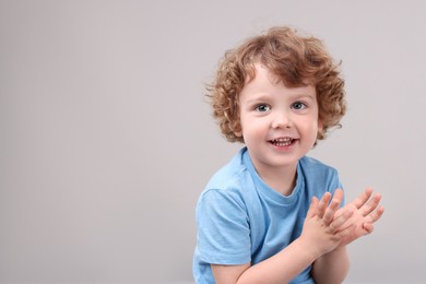 Portrait of cute little boy on grey background, space for text