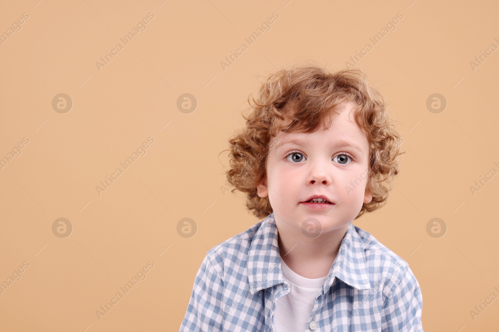 Photo of Portrait of cute little boy on beige background, space for text