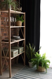 Photo of Shelving unit, green houseplants and elegant curtain in room. Interior design