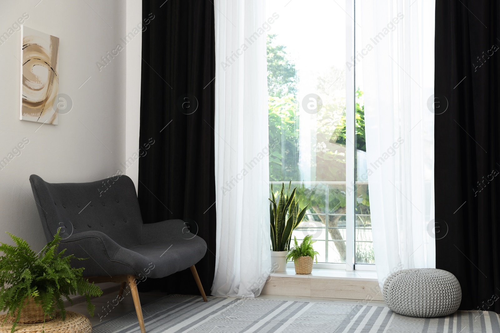 Photo of Sofa, green houseplants, pouffe and elegant curtains in room. Interior design