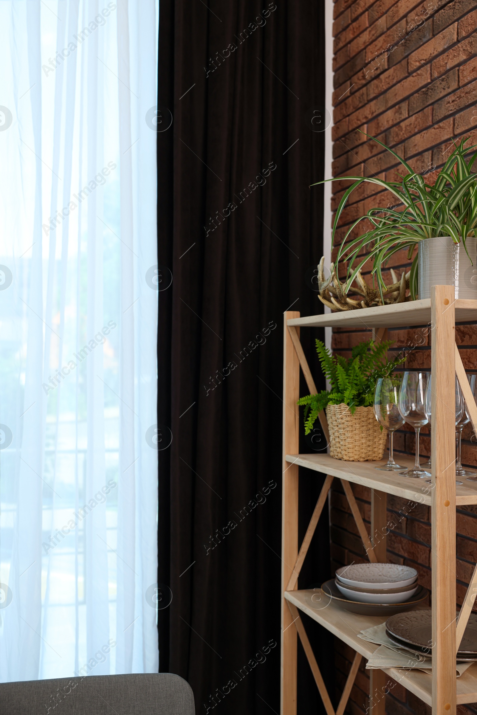 Photo of Shelving unit and elegant curtain in room. Interior design