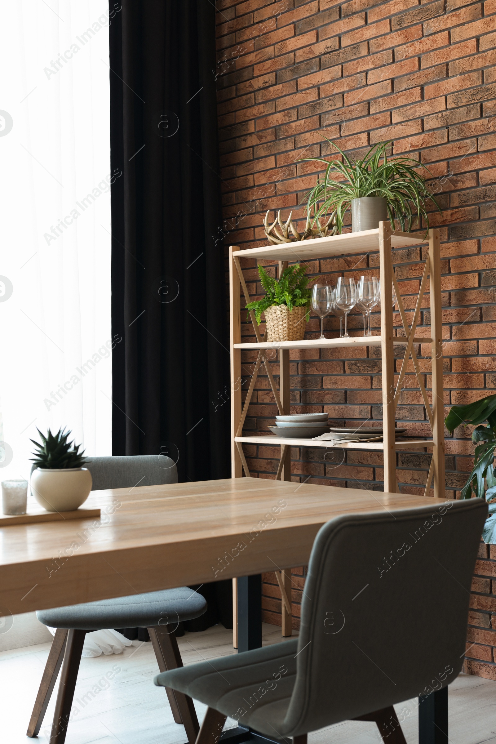 Photo of Shelving unit, table, chairs, green houseplants and elegant curtain in room. Interior design