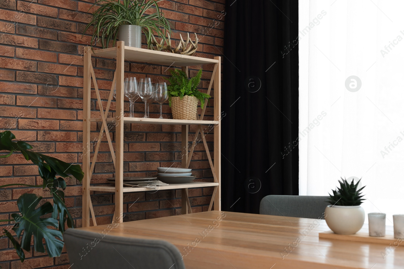 Photo of Shelving unit, table, chairs, green houseplants and elegant curtain in room. Interior design