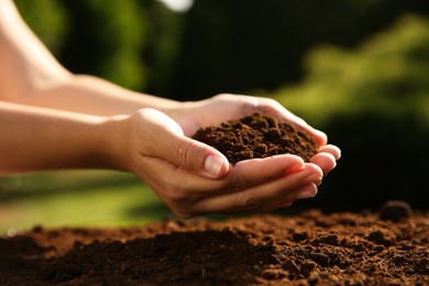 Woman holding pile of soil outdoors, closeup