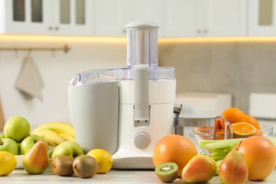 Modern juicer and fruits on white marble table in kitchen