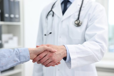 Photo of Doctor shaking hands with patient in clinic, closeup