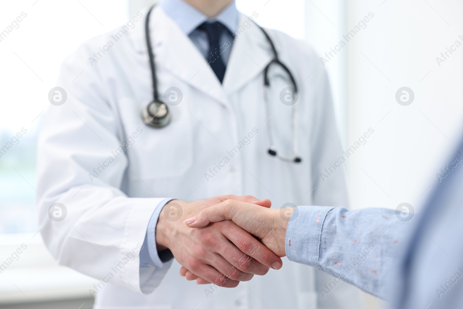 Photo of Doctor shaking hands with patient in clinic, closeup