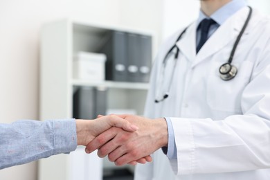 Doctor shaking hands with patient in clinic, closeup