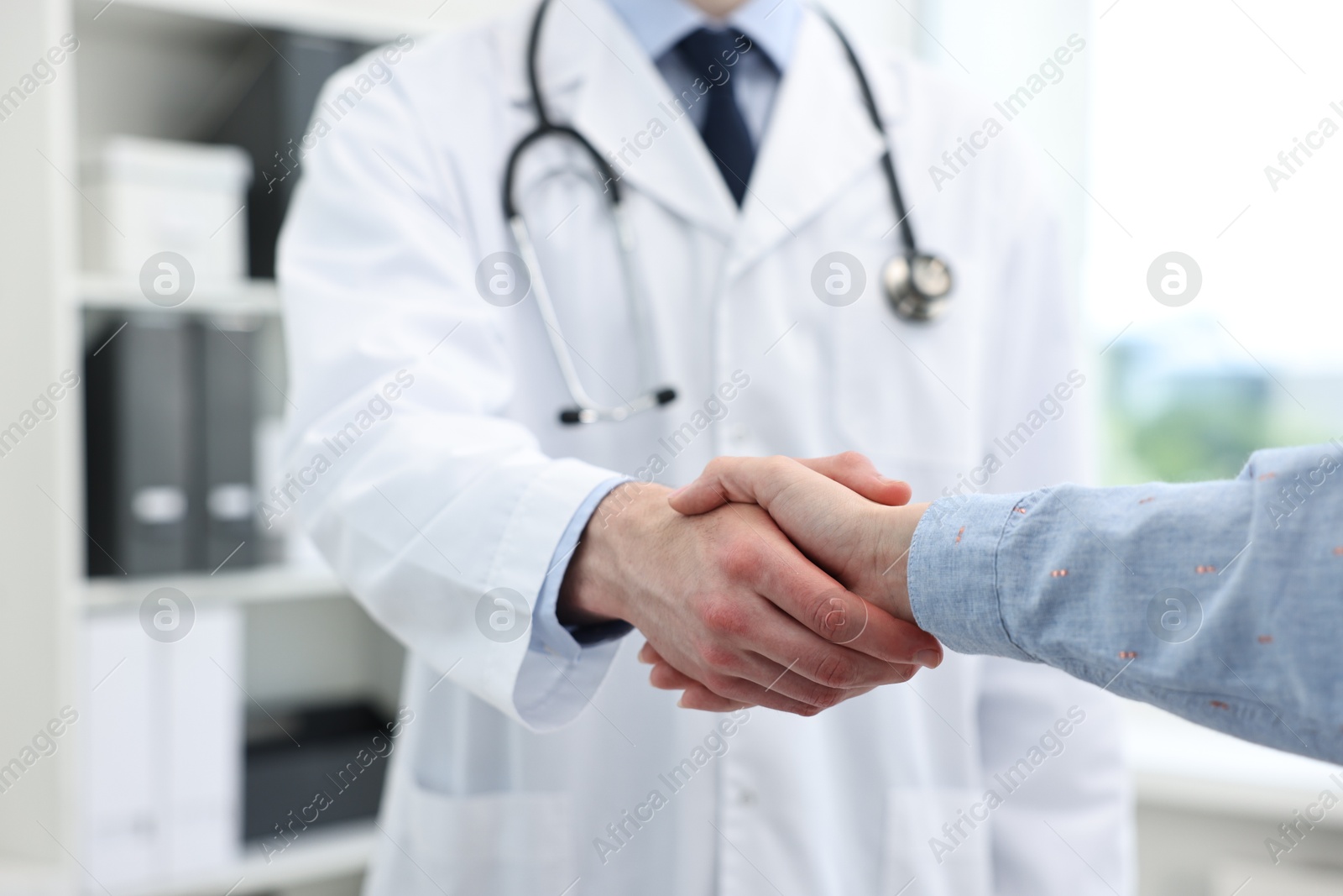 Photo of Doctor shaking hands with patient in clinic, closeup