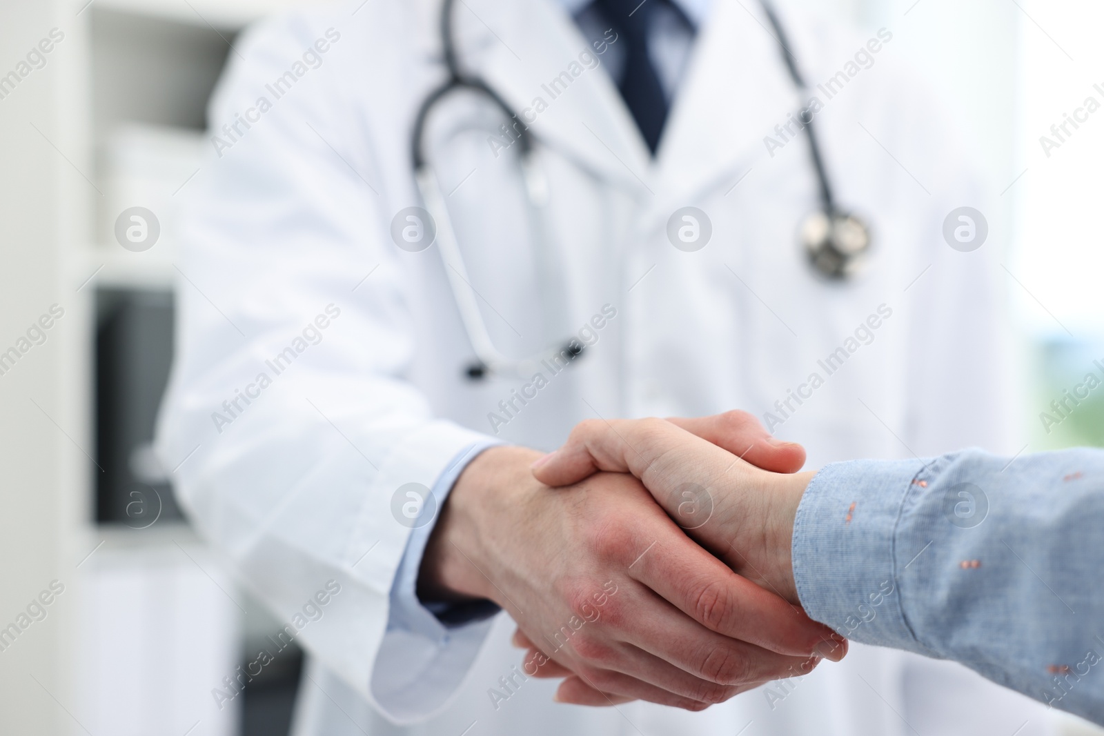 Photo of Doctor shaking hands with patient in clinic, closeup