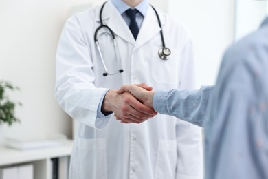 Doctor shaking hands with patient in clinic, closeup