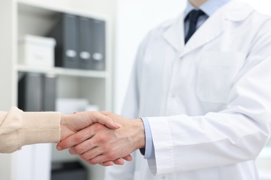 Photo of Doctor shaking hands with patient in clinic, closeup