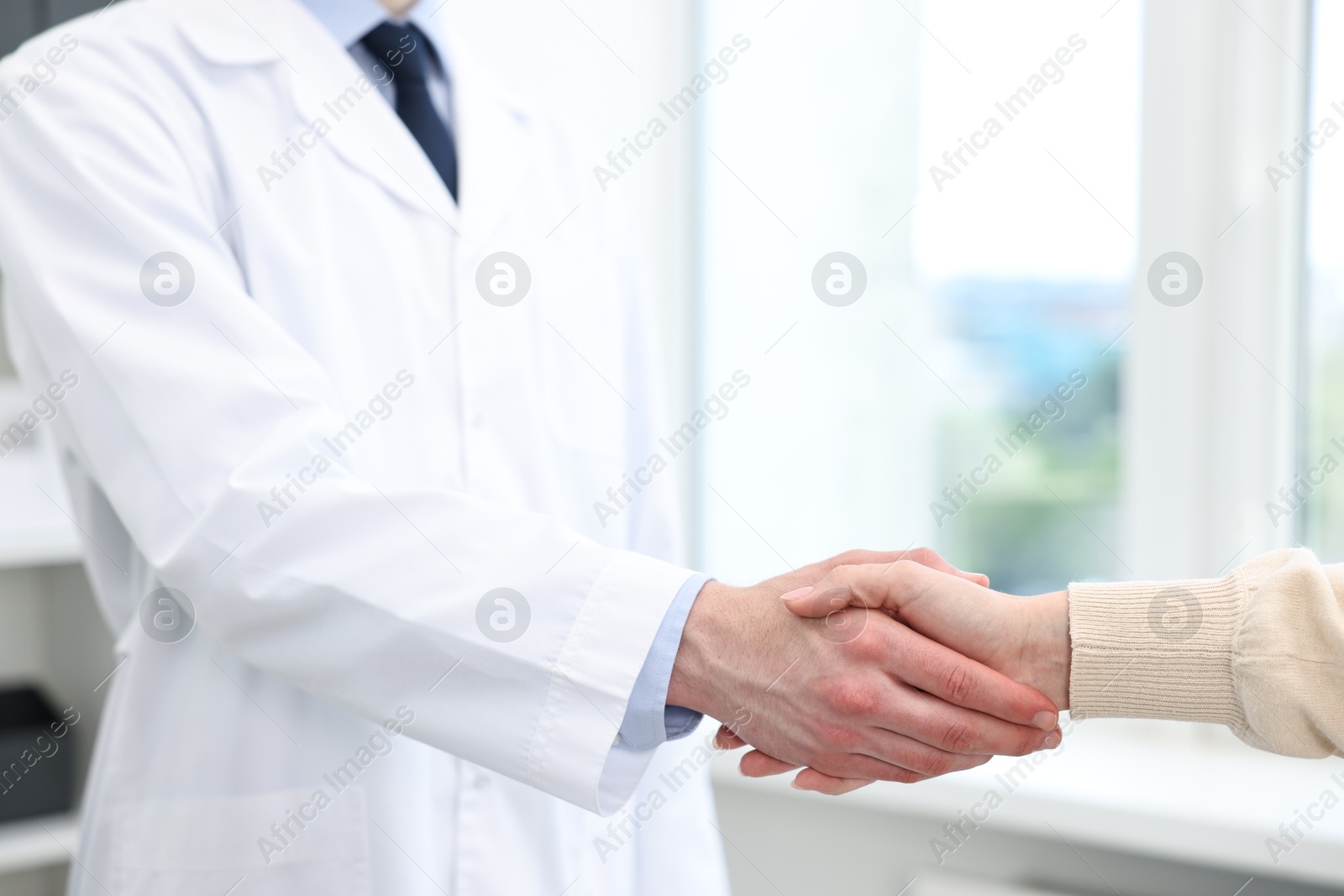 Photo of Doctor shaking hands with patient in clinic, closeup