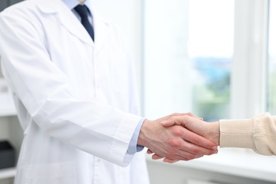 Photo of Doctor shaking hands with patient in clinic, closeup