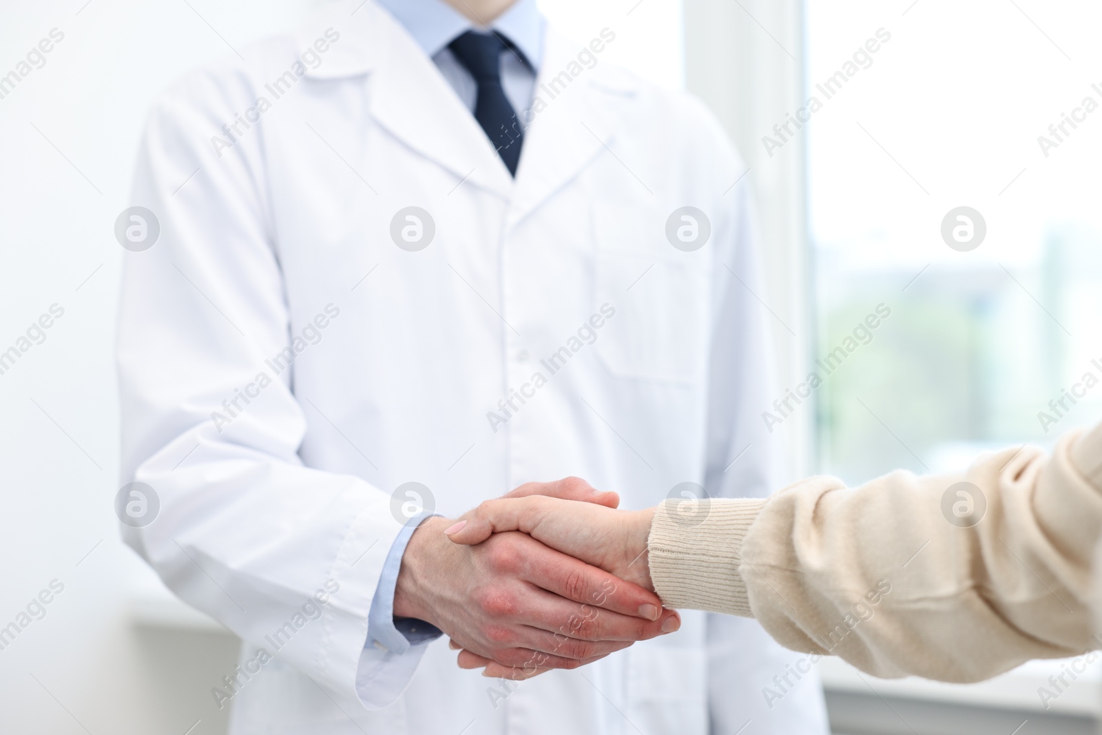 Photo of Doctor shaking hands with patient in clinic, closeup