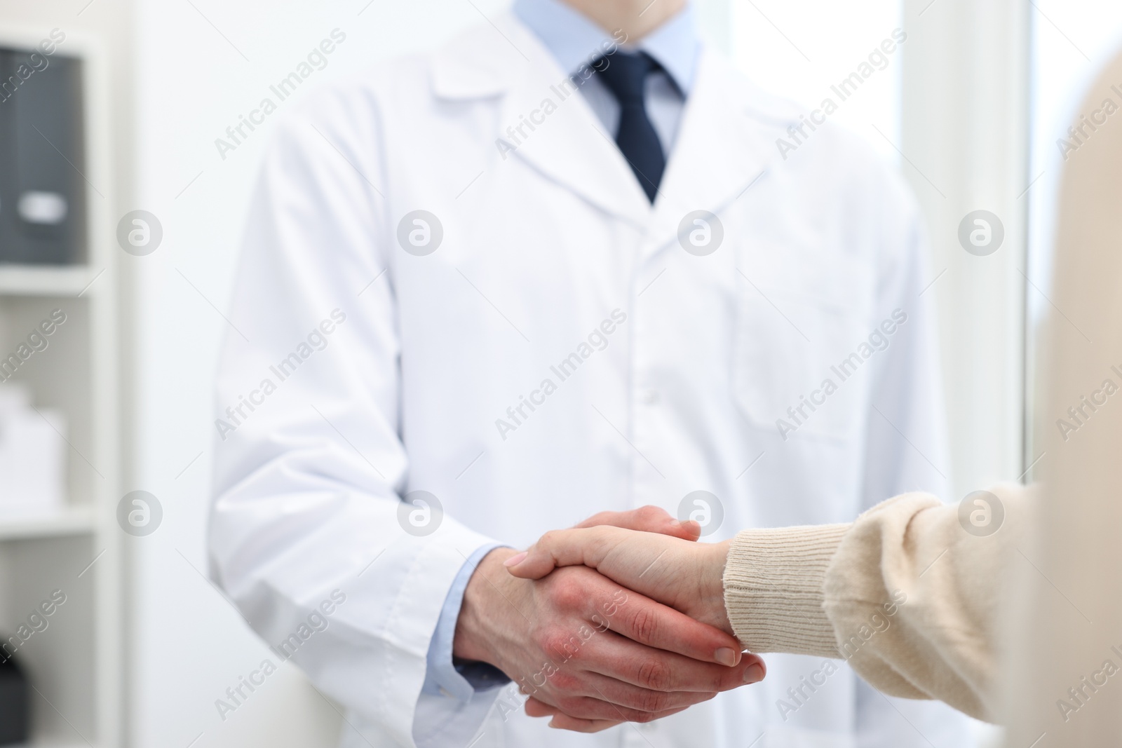 Photo of Doctor shaking hands with patient in clinic, closeup