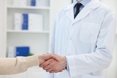 Doctor shaking hands with patient in clinic, closeup