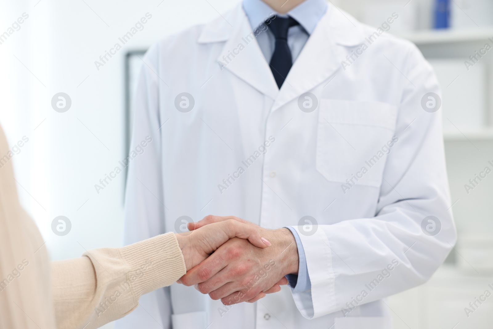 Photo of Doctor shaking hands with patient in clinic, closeup