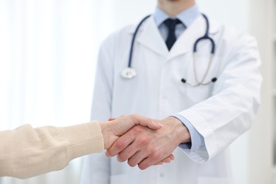 Photo of Doctor shaking hands with patient in clinic, closeup