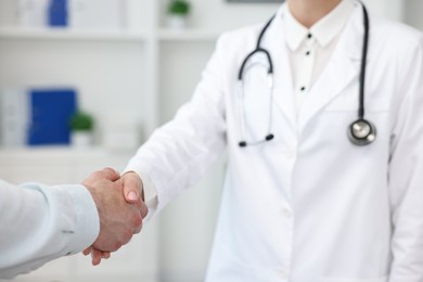 Photo of Doctor shaking hands with patient in clinic, closeup