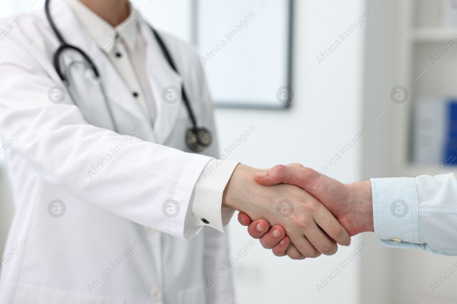 Photo of Doctor shaking hands with patient in clinic, closeup