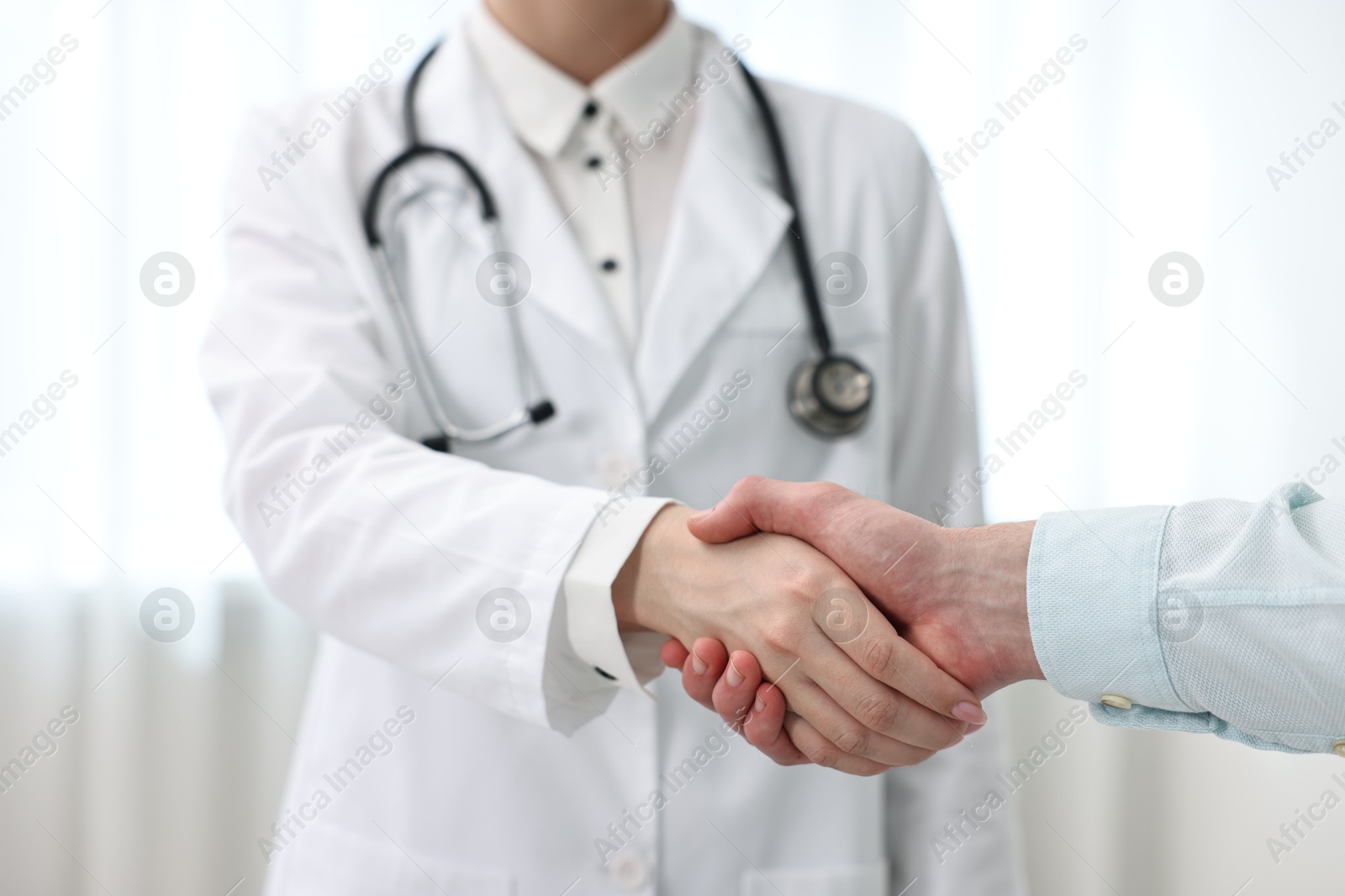 Photo of Doctor shaking hands with patient in clinic, closeup