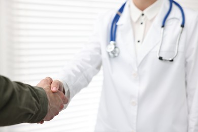 Photo of Doctor shaking hands with patient in clinic, closeup