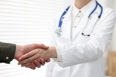 Photo of Doctor shaking hands with patient in clinic, closeup