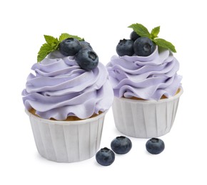 Photo of Tasty cupcakes with blueberries and mint isolated on white