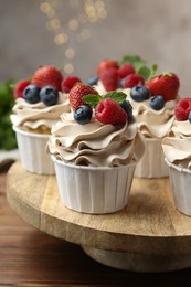 Photo of Tasty cupcakes with different berries and mint on wooden table, closeup