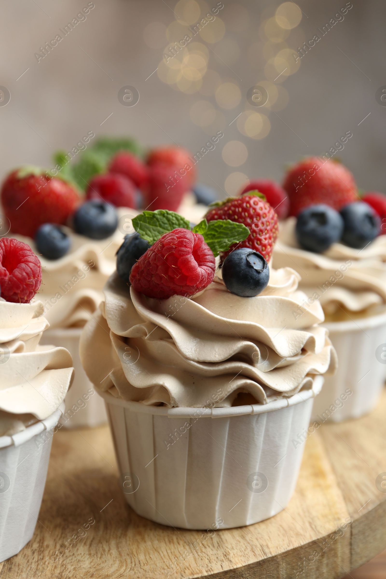 Photo of Tasty cupcakes with different berries and mint on wooden table, closeup