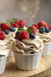 Photo of Tasty cupcakes with different berries and mint on wooden table, closeup