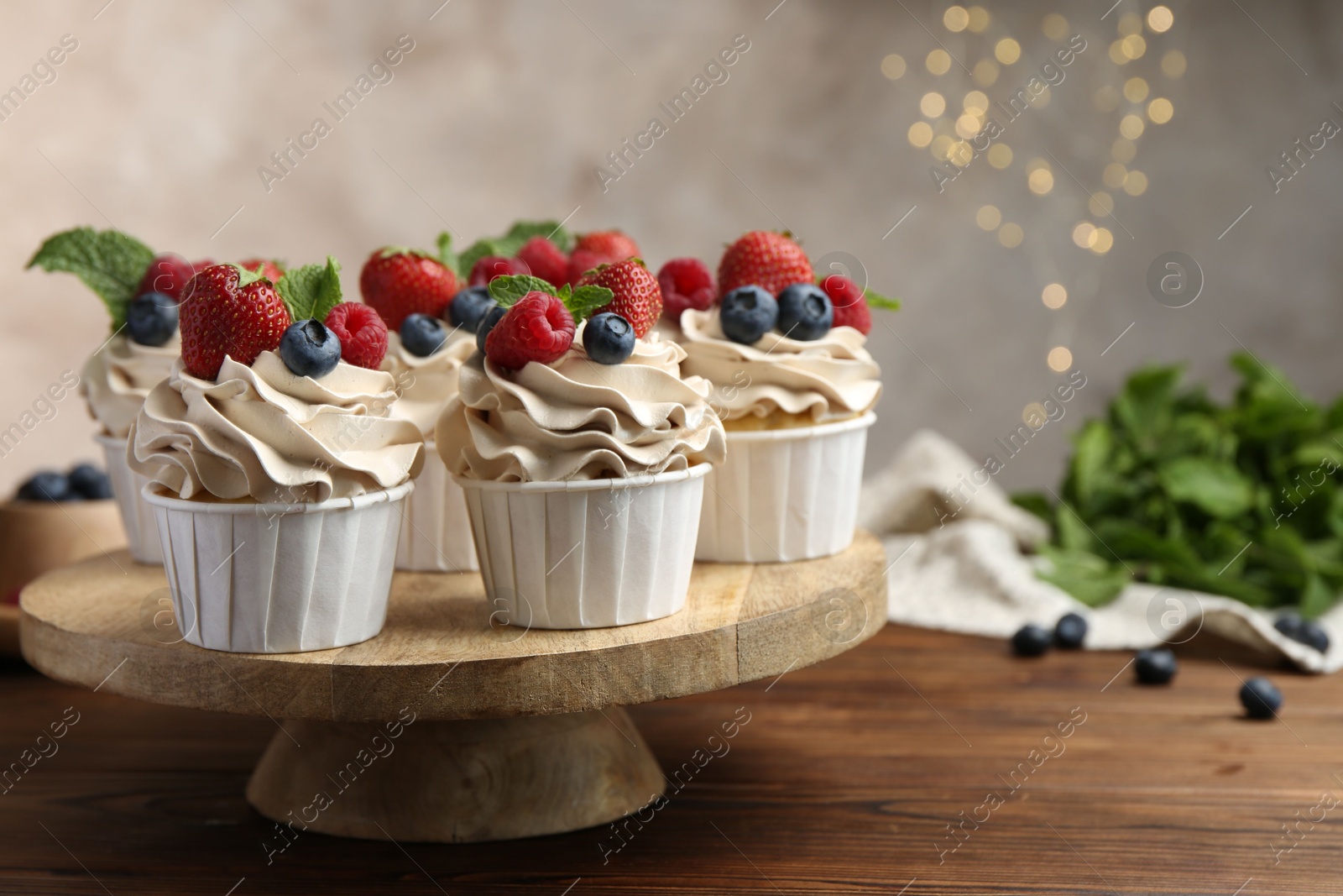 Photo of Tasty cupcakes with different berries and mint on wooden table, closeup. Space for text