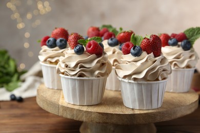 Photo of Tasty cupcakes with different berries and mint on wooden table, closeup