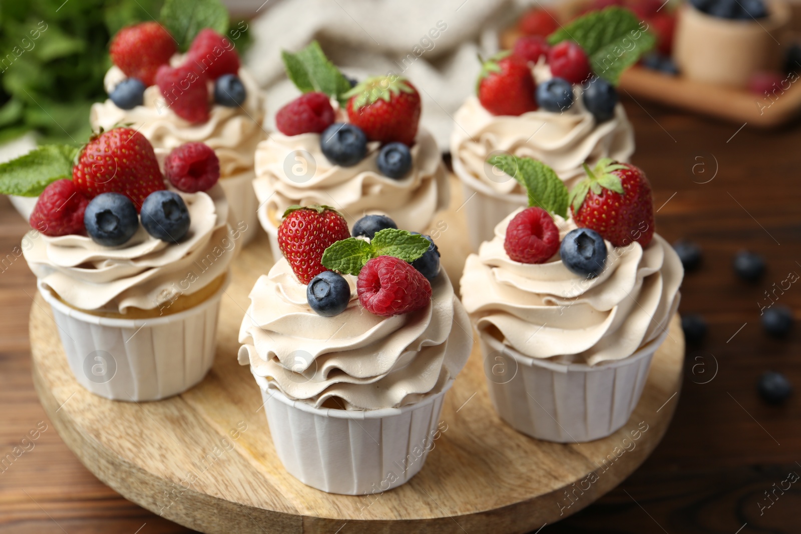 Photo of Tasty cupcakes with different berries and mint on wooden table, closeup