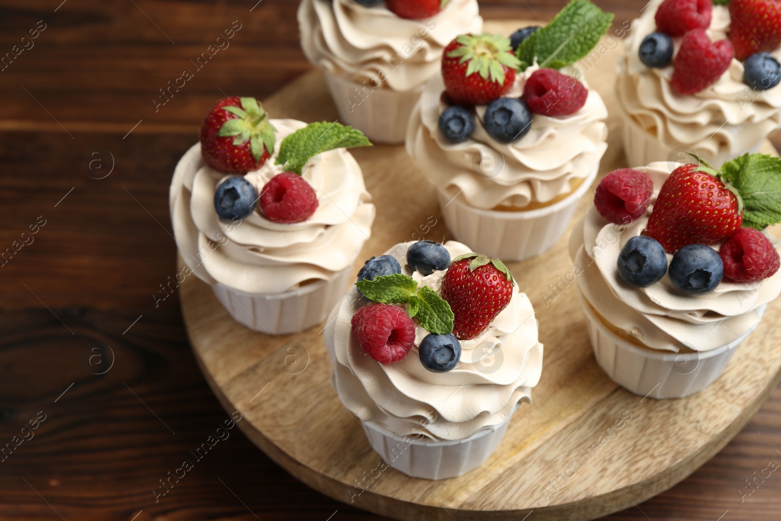 Photo of Tasty cupcakes with different berries and mint on wooden table, closeup