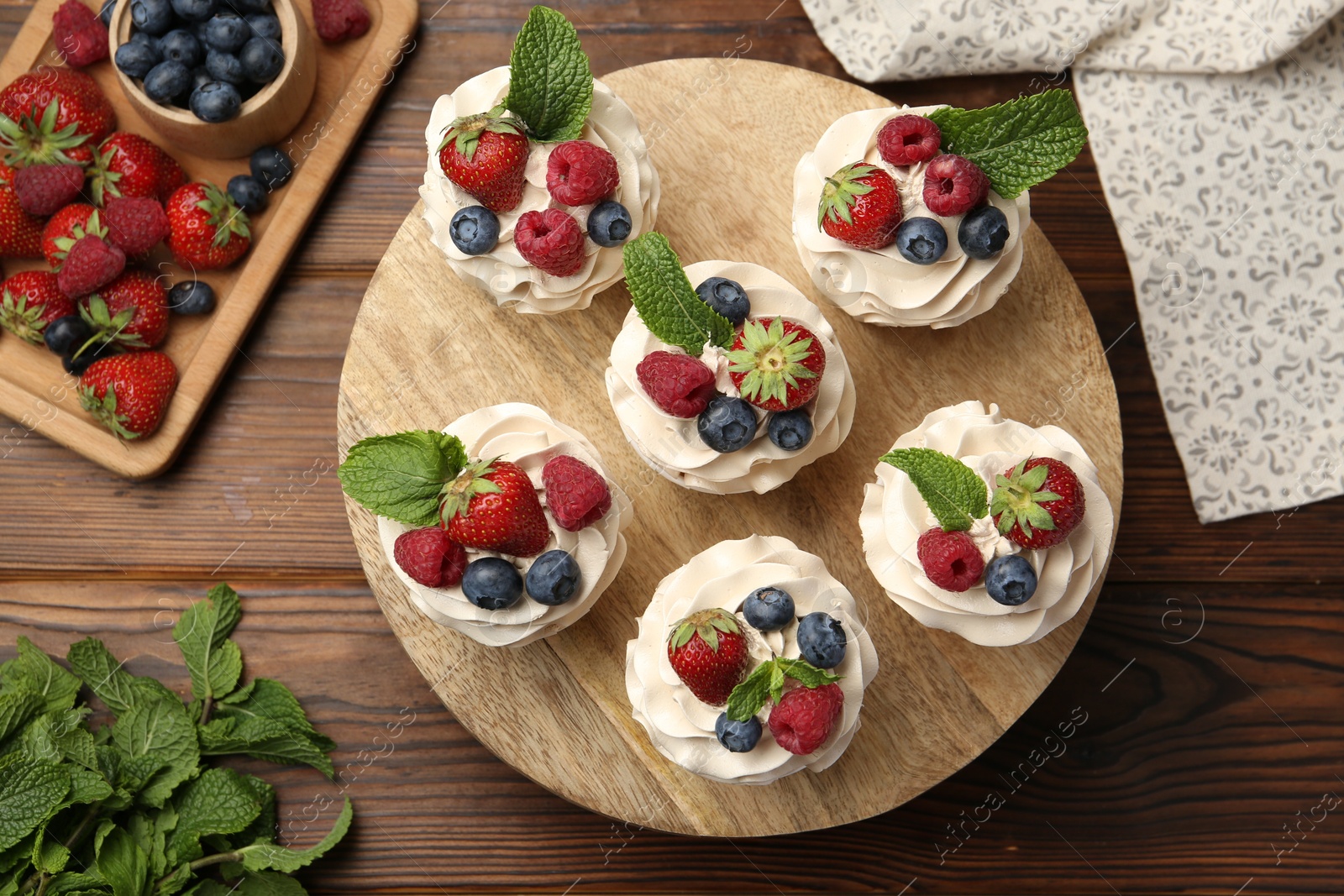 Photo of Tasty cupcakes with different berries and mint on wooden table, flat lay