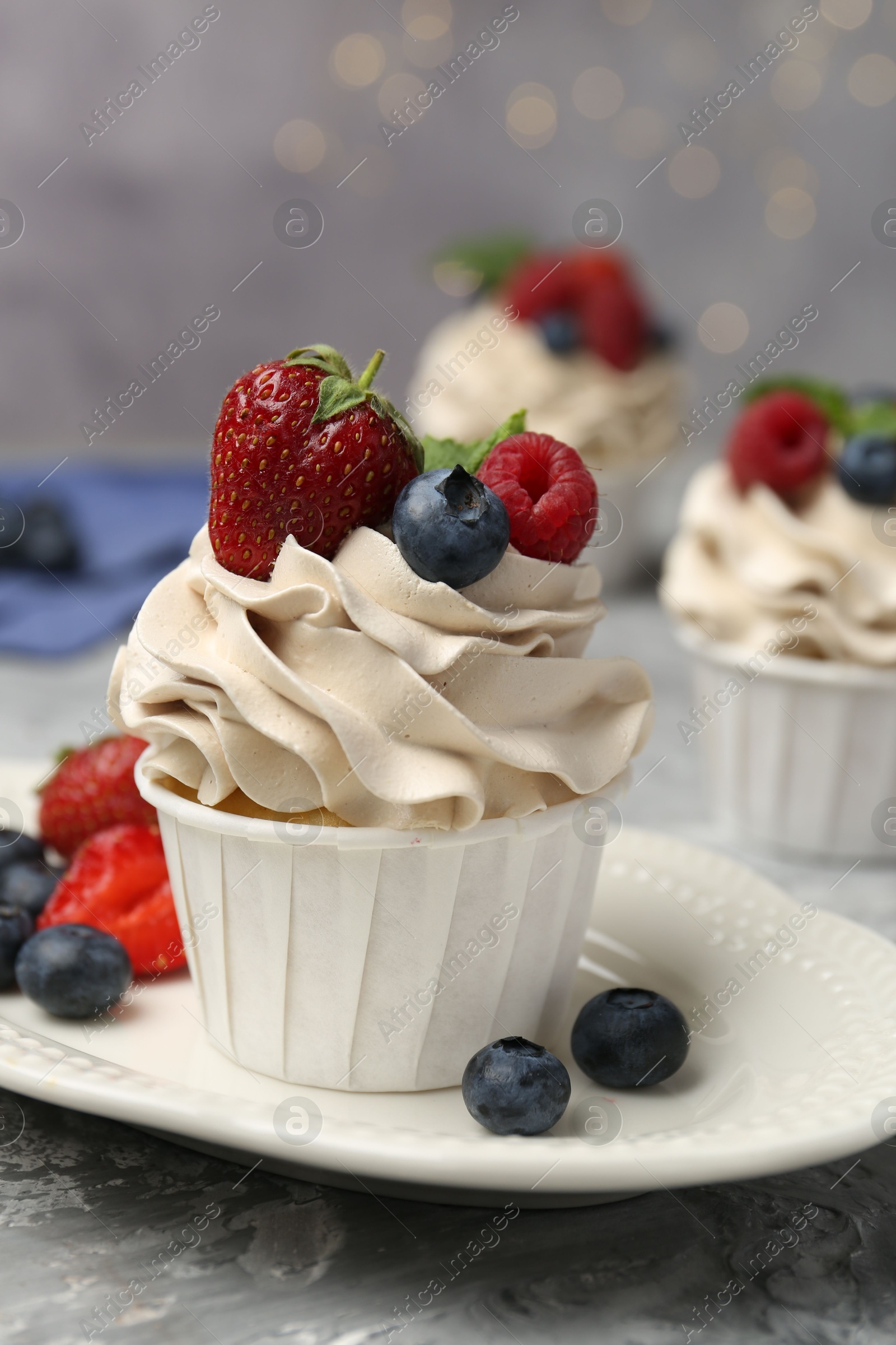 Photo of Tasty cupcake with different berries on light grey table, closeup