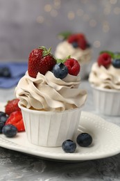 Photo of Tasty cupcake with different berries on light grey table, closeup