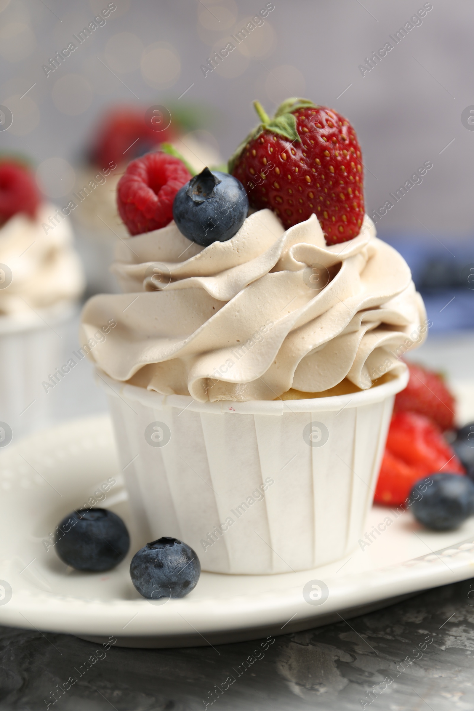 Photo of Tasty cupcake with different berries on light grey table, closeup