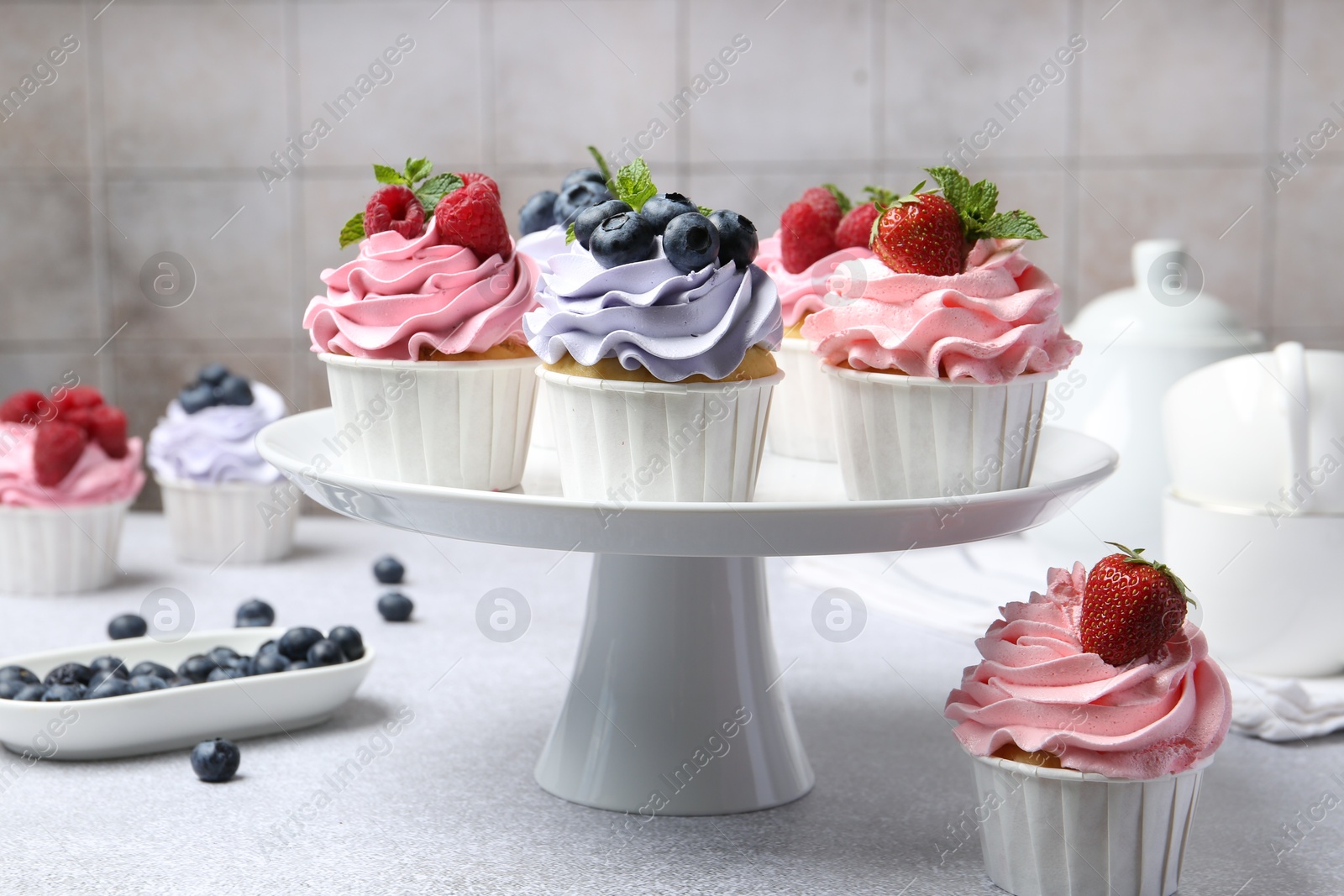 Photo of Tasty cupcakes with different berries on light grey table